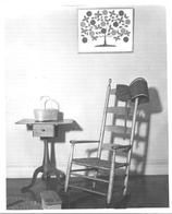 SA0649 - Photograph of a sewing stand, a rocking chair with arms, a foot rest, and an inspirational painting.